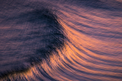 Blurred motion of oceans surface with pink and golden hues