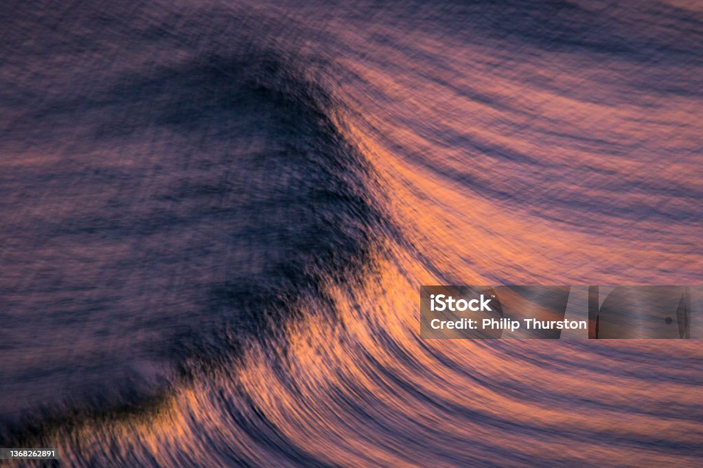 Blurred motion of oceans surface with pink and golden hues Abstract Stock Photo