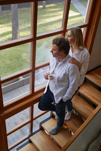 istock Tender woman standing behind her husband near window 1368263002