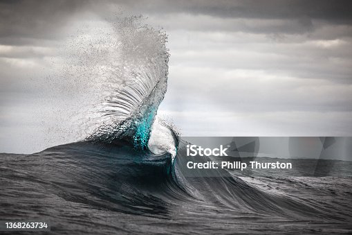 istock Close up of ocean wave twisting into air in front of grey moody sky 1368263734