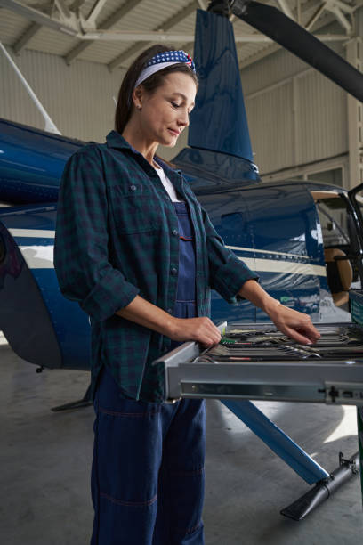 istock Joyful elegant relief female engineer in uniform in front of the helicopter 1368263803