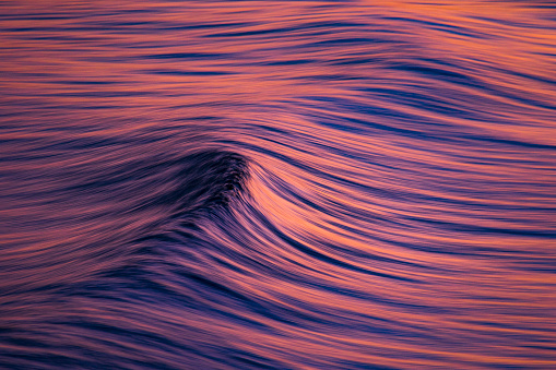 Long exposure of ocean surface in pink golden light