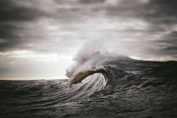 formación de olas oceánicas frente a cielos grises oscuros - ambiente atmosférico fotos fotografías e imágenes de stock