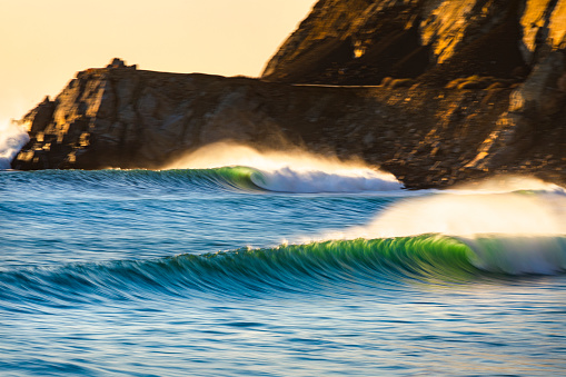 Perfect waves forming in front of rocky California coastline