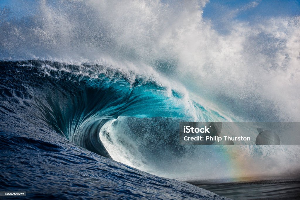 Powerful crashing ocean wave with hint of rainbow shining through Wave - Water Stock Photo