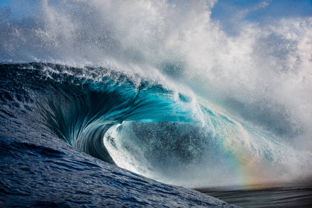 Powerful crashing ocean wave with hint of rainbow shining through Powerful crashing ocean wave with hint of rainbow shining through power in nature stock pictures, royalty-free photos & images