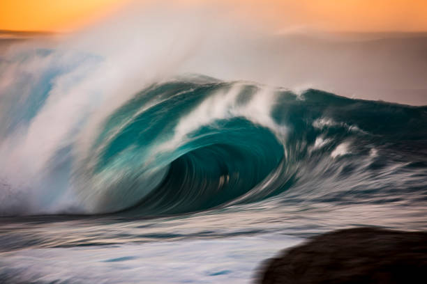 istock Powerful crashing turquoise wave in front of golden sky 1368264617