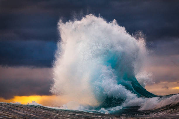 mächtige welle, die während des mehrfarbigen sonnenuntergangs in den himmel explodiert - green sky water wave stock-fotos und bilder