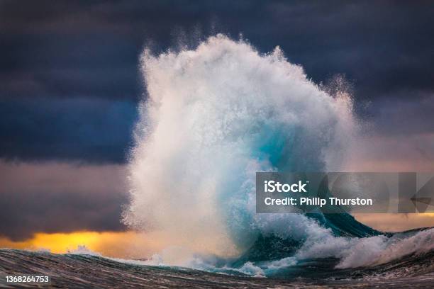 Powerful Wave Exploding Into Sky During Multi Colored Sunset Stock Photo - Download Image Now