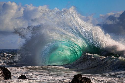 Powerful turquoise wave explosion crashing against rocks