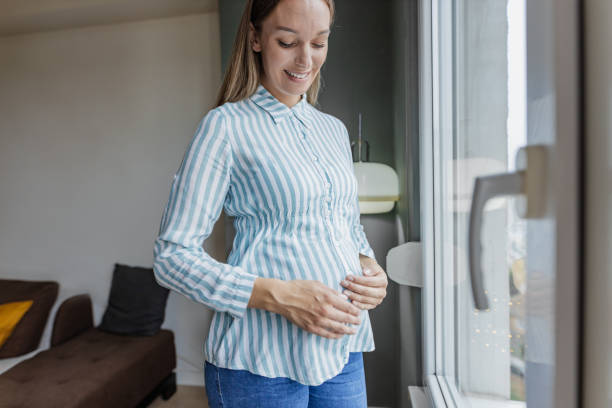 istock Pregnant woman standing by the window 1368264774