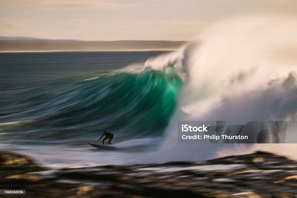 Slow shutter of surfer riding perfect green wave Surfing Stock Photo