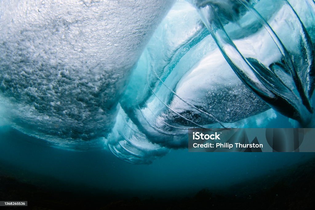 View from underneath a crashing ocean wave View from underneath a bright blue crashing ocean wave Wave - Water Stock Photo