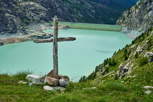 A christian wooden cross with rosary beads. Alpe Fellaria. The Fellaria glacier in the background. Lanzada Municipality. Province of Sondrio. Italy.