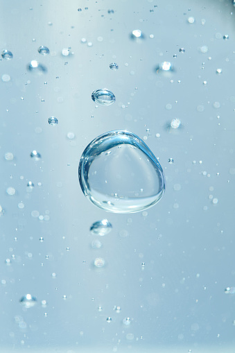 Round and blue floating bubbles similar to hyaluronic acid. Shallow depth of field.
