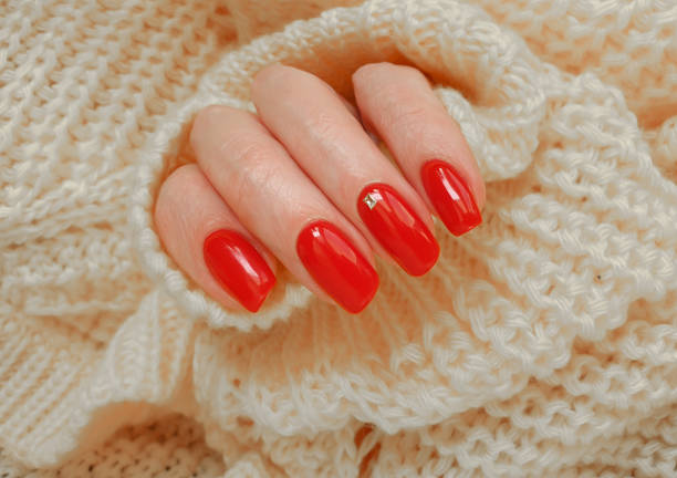 istock beautiful red manicure female hand, yellow sweater 1368272768
