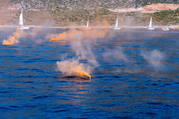 istock Orange colored smoke grenade with sail boats. Distress call 1368273033