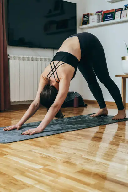 Photo of An Anonymous Woman Practicing Yoga in the Morning, Doing Downward Facing Dog Exercise