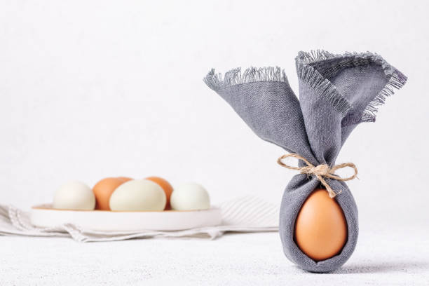 istock Easter egg decorated with a napkin in the shape of a bunny on a white concrete background 1368274443