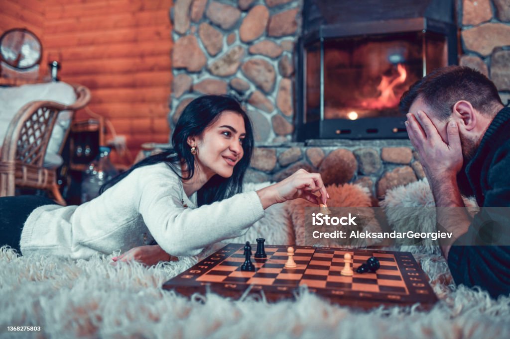 Male Getting Check Mate By Girlfriend While Relaxing By Cottage Fireplace Checkmate Stock Photo