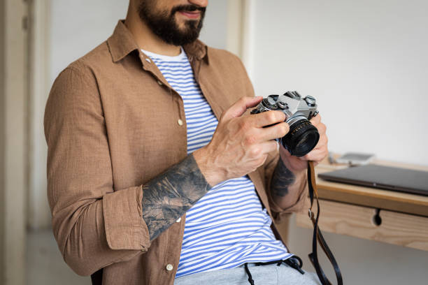 A cropped image of an unrecognisable photographer playing around with his film camera.