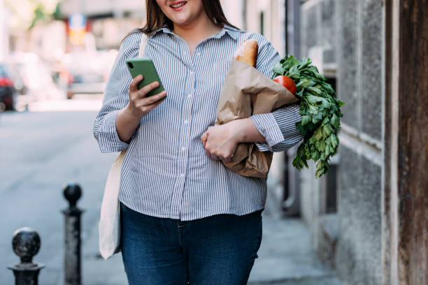 istock An Anonymous Female Texting On Her Mobile Phone While Holding A Reusable Bag With Groceries 1368277149