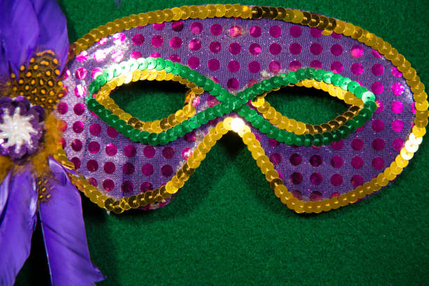 LV Mardi Gras sequined mask, decorated with feathers.  Green background.