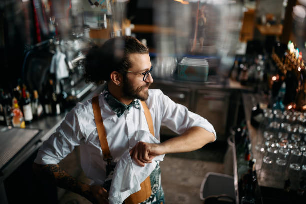 istock Happy man cleaning drinking glasses while working as barista in a pub. 1368278251