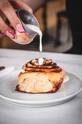 Woman pouring milk on to cinnamon roll