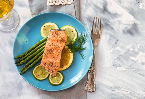 filetto di salmone alla griglia con asparagi servito su un piatto - salmone arrosto foto e immagini stock