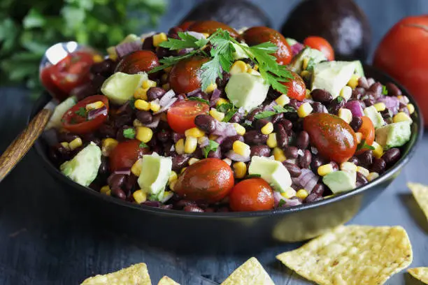 Homemade Mexican black bean and corn salad or Texas caviar bean dip lime dressing, Served with tortilla chips and fresh ingredients.