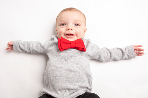 A 5 month old baby boy wearing a red bow tie.