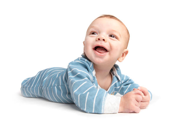 Color photo of a laughing baby boy lying on his back on a textured blanket.