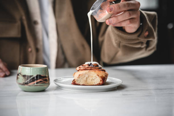 Man pouring milk on to cinnamon roll stock photo