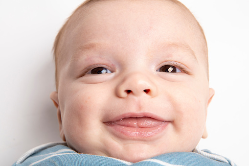 A close up of a 5 month old baby boy with a big smile.