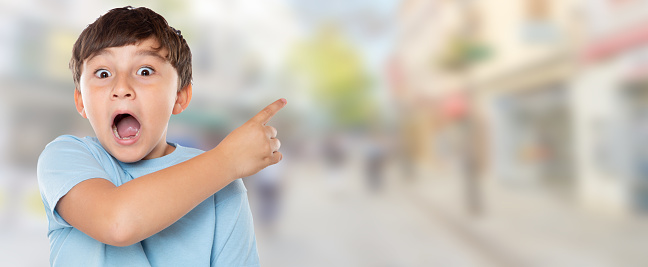 Child kid amazed surprised little boy pointing on ad advertising in town with copyspace copy space city