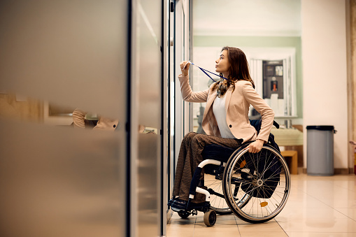 Joven empresaria en silla de ruedas con tarjeta de acceso para entrar en la oficina. photo