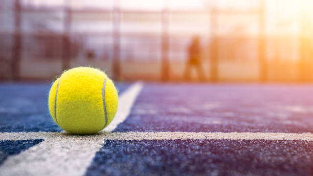 yellow ball on floor behind paddle net in blue court outdoors. padel tennis - padel stockfoto's en -beelden