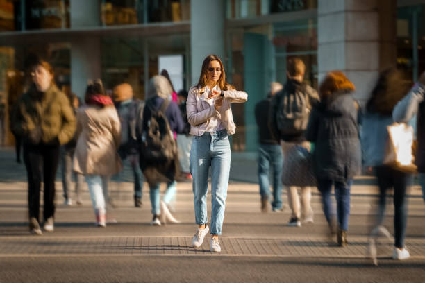 mujer joven caminando en medio de una calle abarrotada y mirando el tiempo a mano observa. vida en la gran ciudad. - blurred motion motion group of people crowded fotografías e imágenes de stock