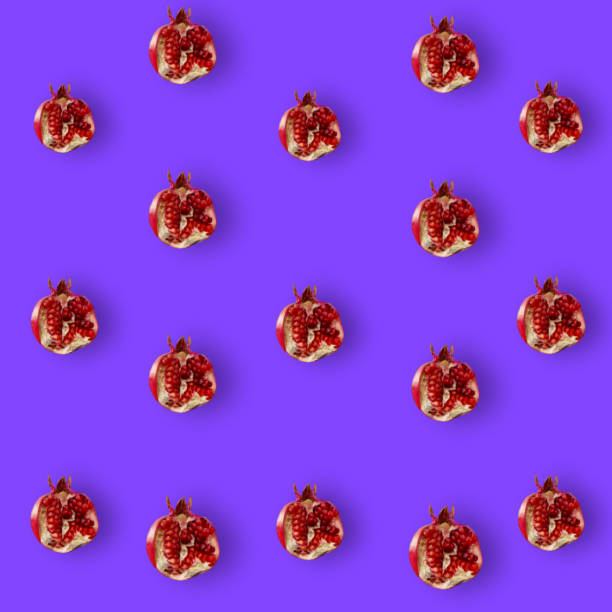 istock Colorful fruit pattern of fresh pomegranates on purple background. Top view. Flat lay. Pop art design 1368290742