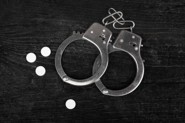 istock metal handcuffs on a black background with white narcotic pills 1368292769