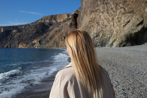 young beautiful woman on the seashore against the background of rocks.