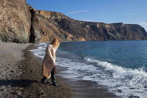 a young beautiful woman runs along a pebble beach against the backdrop of sea