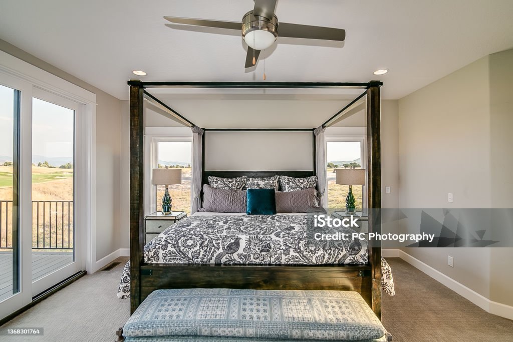 Four poster canopy bed Windows all around in master bedroom allowing for amazing views Owner's Bedroom Stock Photo
