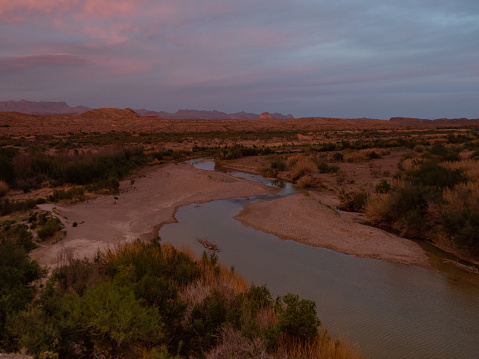 Santa Elena Canyon at the golden hour with the Rio Grande River in the foreground and the Chisos Mountain Range in the background. Photographed in Big Bend National Park, Texas.