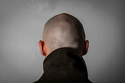 Young man with shaved head and thick winter coat prepares to go out. Very Eastern European.