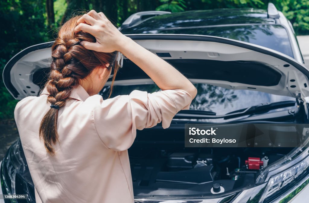 Asian woman opened car hood for looking the problem of car breakdown while waiting for assistance on the road side. Car breakdown it will happen to you at least once in your driving life. Car Stock Photo