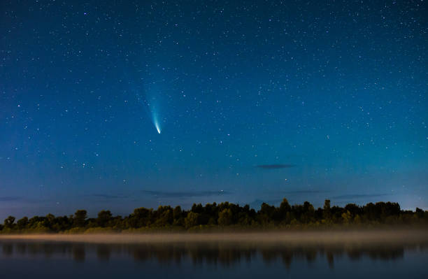 komet am nachthimmel. sommerlicher sternenhimmel. sterne am himmel. schöne nachtlandschaft. langzeitbelichtung. konzeptuelle fotografie. nebel über dem wasser. atmosphärische landschaft. morgendämmerung. komet neowise - komet stock-fotos und bilder