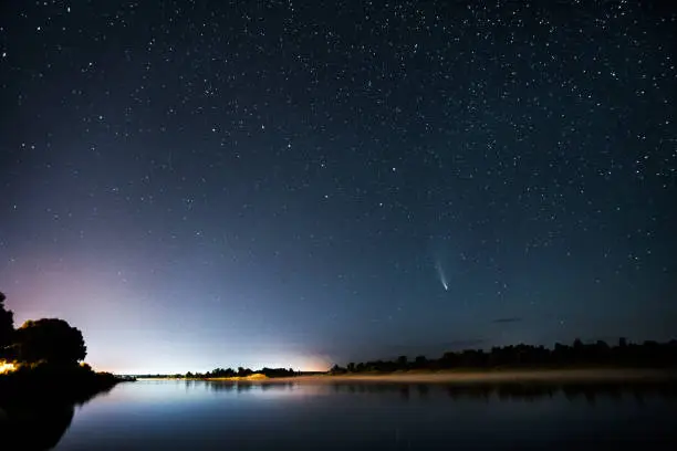 Photo of Comet in the night sky. Summer starry sky. Stars on the sky. Beautiful night landscape. Long exposure