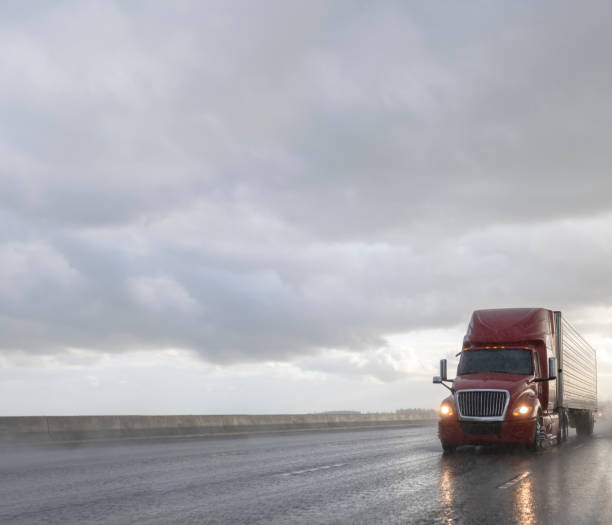 istock Big rig professional semi truck transporting cargo in reefer semi trailer running on the wet highway with rain and water dust 1368307077